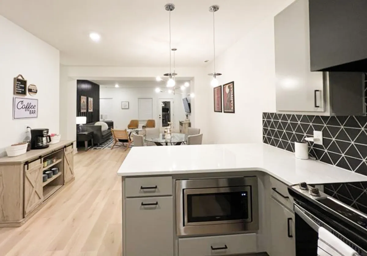 A cozy, contemporary kitchen and dining area with a central island, a dedicated coffee bar, and a spacious dining table. The space is filled with natural light, creating a warm setting ideal for both casual breakfasts and festive dinners.